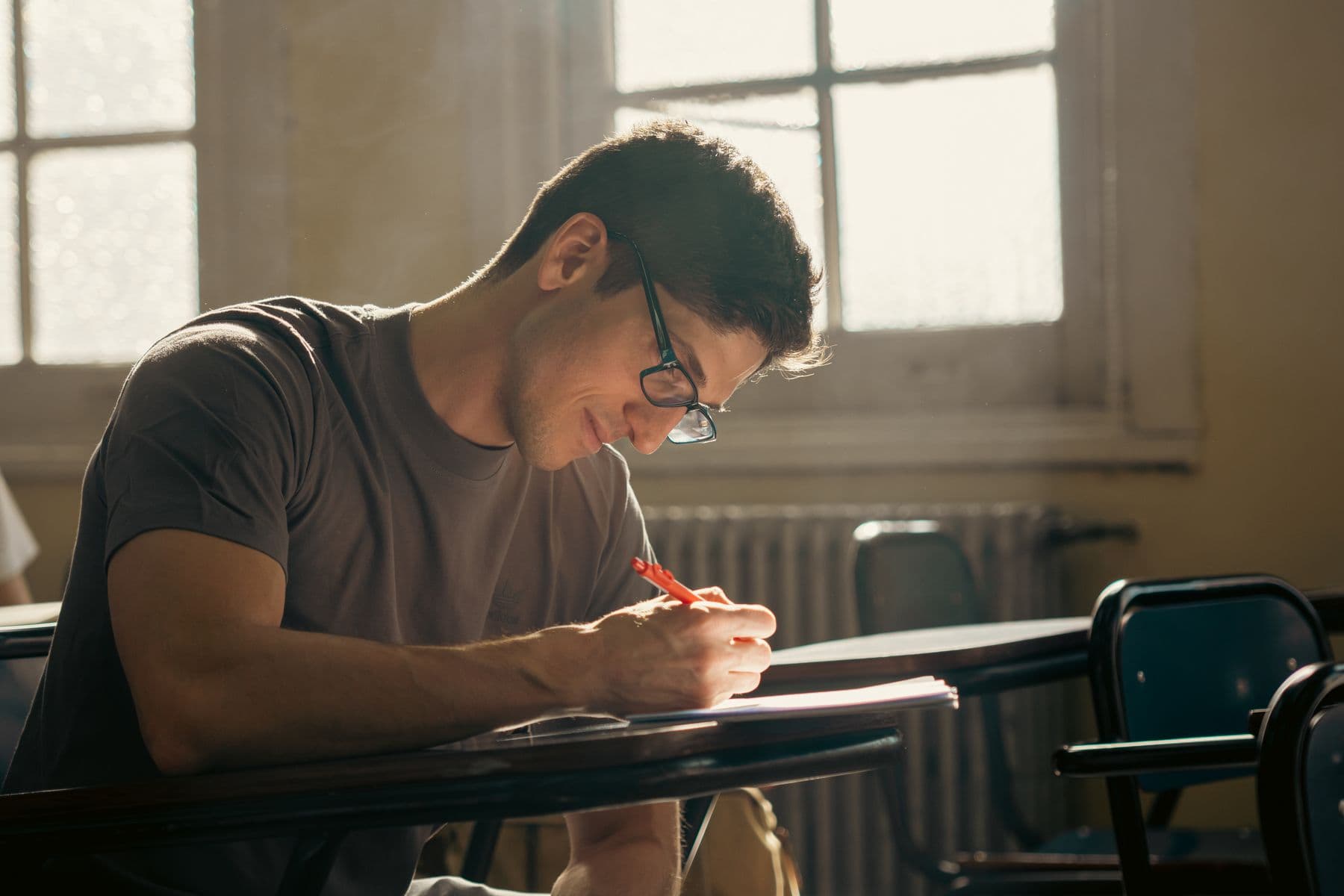 A student writing at a classroom desk